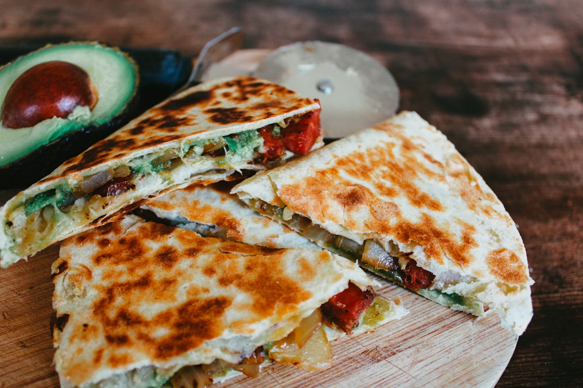 Golden quesadilla wedges on a cutting board with salsa on the side